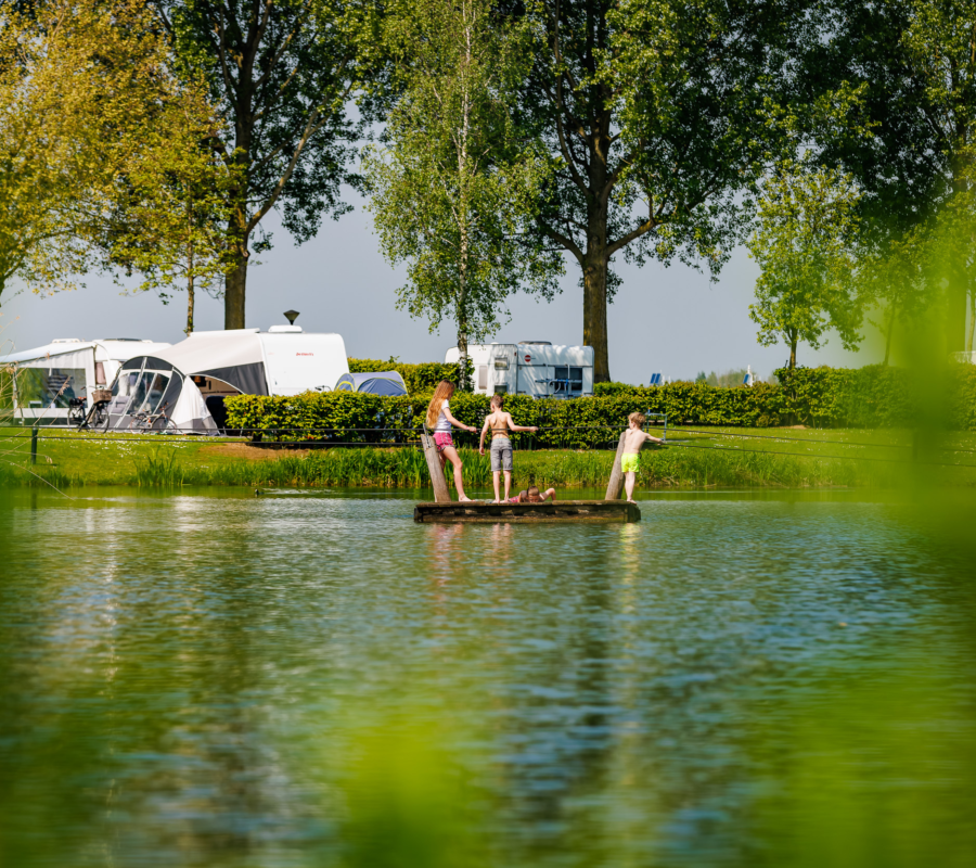 Kinderen die met een vlot oversteken op de vijver van de Rozenwiel
