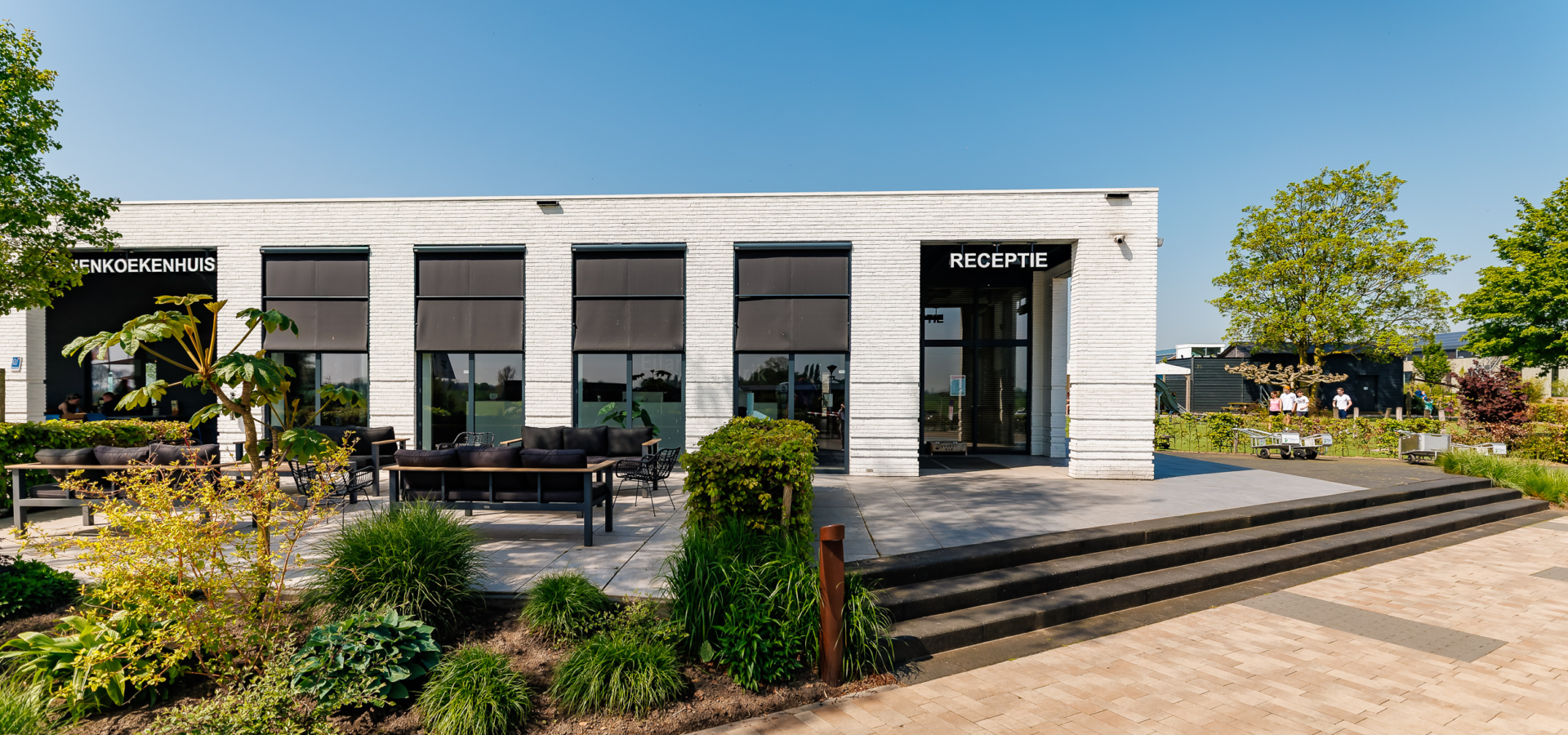 Het receptiegebouw vanaf de buitenkant met groen en een blauwe lucht