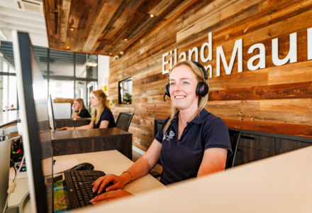 Een receptionisten die met een lach een gast helpen met hun reservering