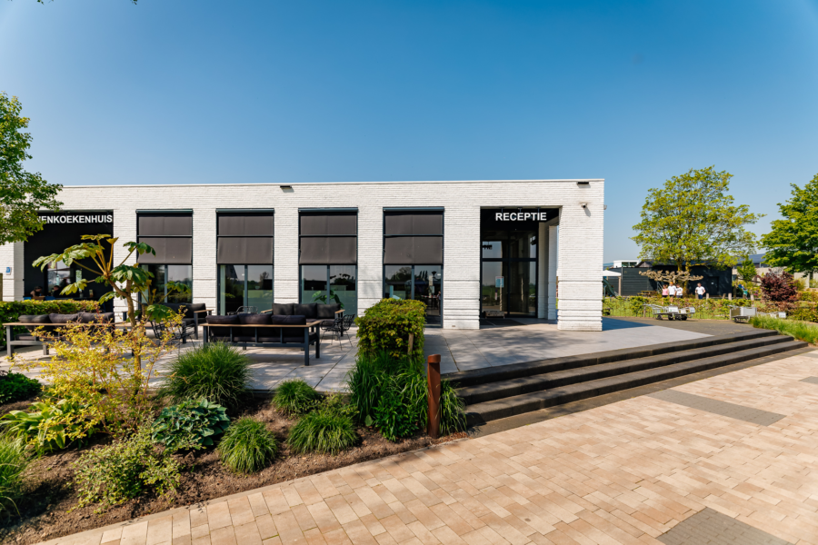 Het receptiegebouw vanaf de buitenkant met groen en een blauwe lucht